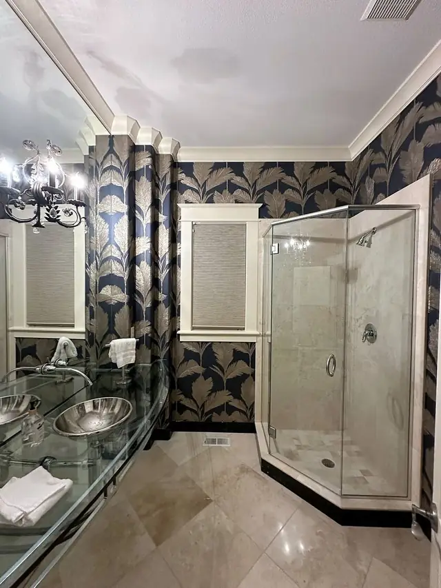 Navy and gold palm-leaf paper wallpaper installed in a bathroom